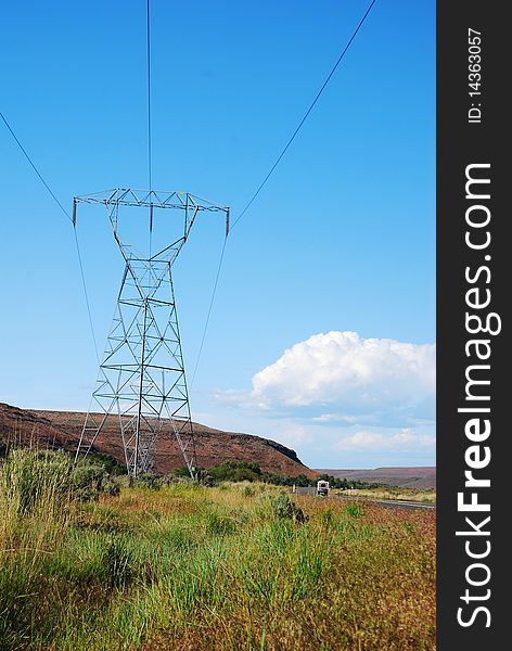 A single power line in Central Washington State against a blue sky with cumulus clouds