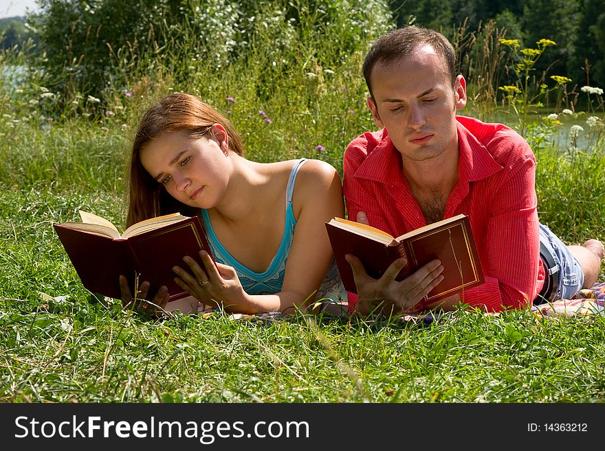 Couple Reading And Relaxing At The Park.