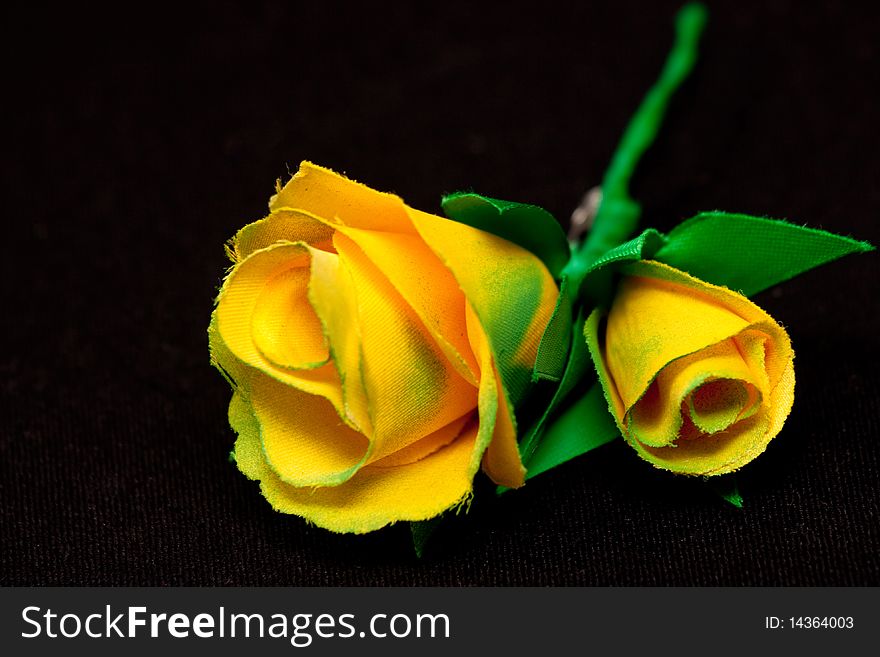 Two yellow artificial handmade roses on black background