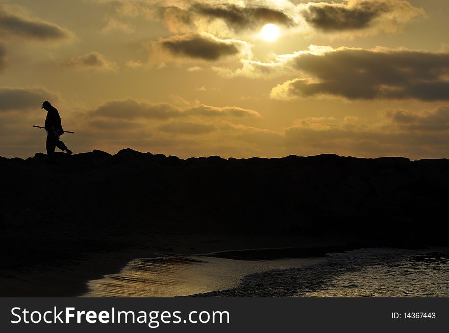 A silhouette of fisherman walking at sunset time. A silhouette of fisherman walking at sunset time