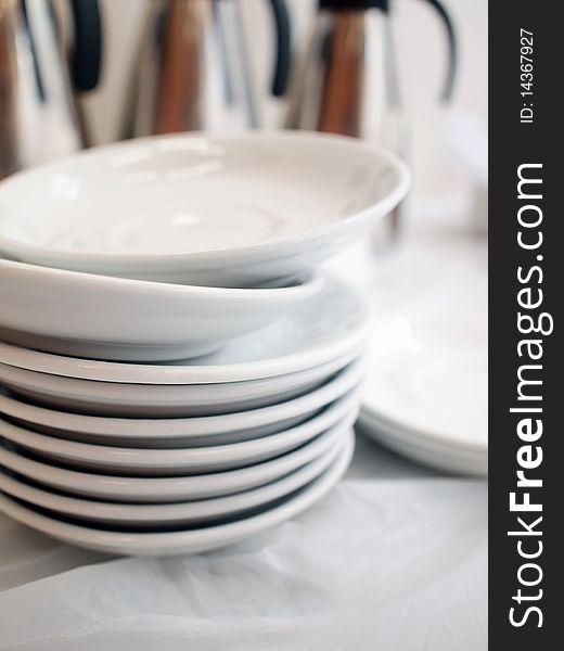 A pile of white plates forming a tower in restaurant. A pile of white plates forming a tower in restaurant