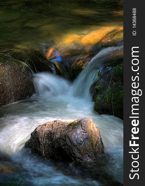 Detail of river rapid with moving water and light reflecting sky and color of rocks. Detail of river rapid with moving water and light reflecting sky and color of rocks