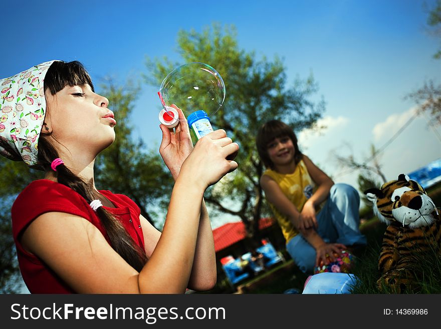 Girl in hat with soap bubbles and boy