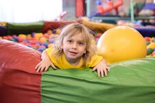Portrait Of A Blond Boy In A Yellow T-shirt. The Child Smiles And Plays In The Children`s Playroom. Ball Pool Stock Photo