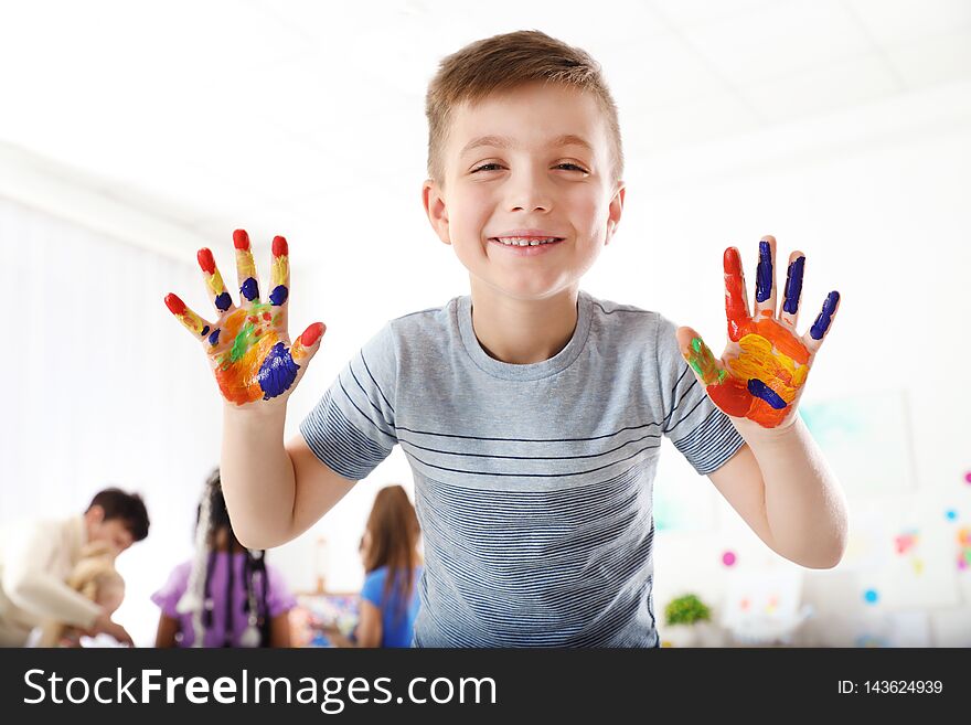 Cute little child showing painted hands at lesson indoors