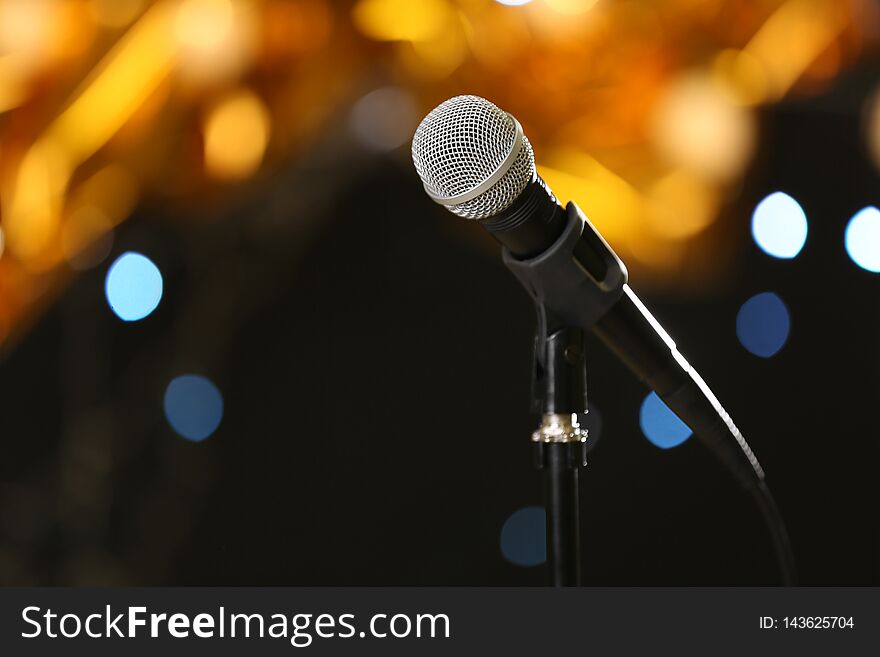 Microphone against festive lights, space for text. Musical equipment