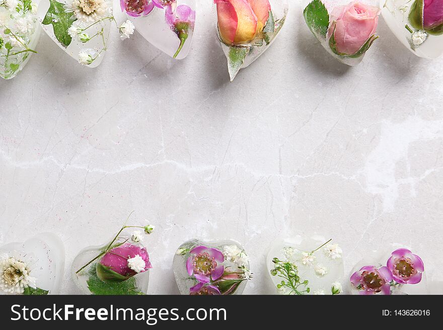 Frame made of heart shaped floral ice cubes on color background, top view