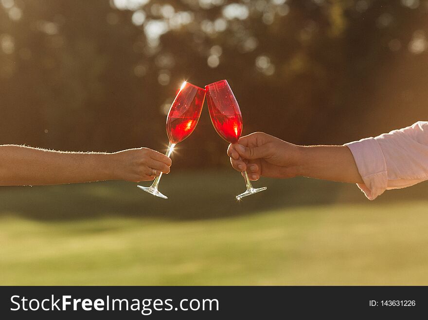 Two Red Wine Glasses In Woman Hand And Man Hand On Nature Background