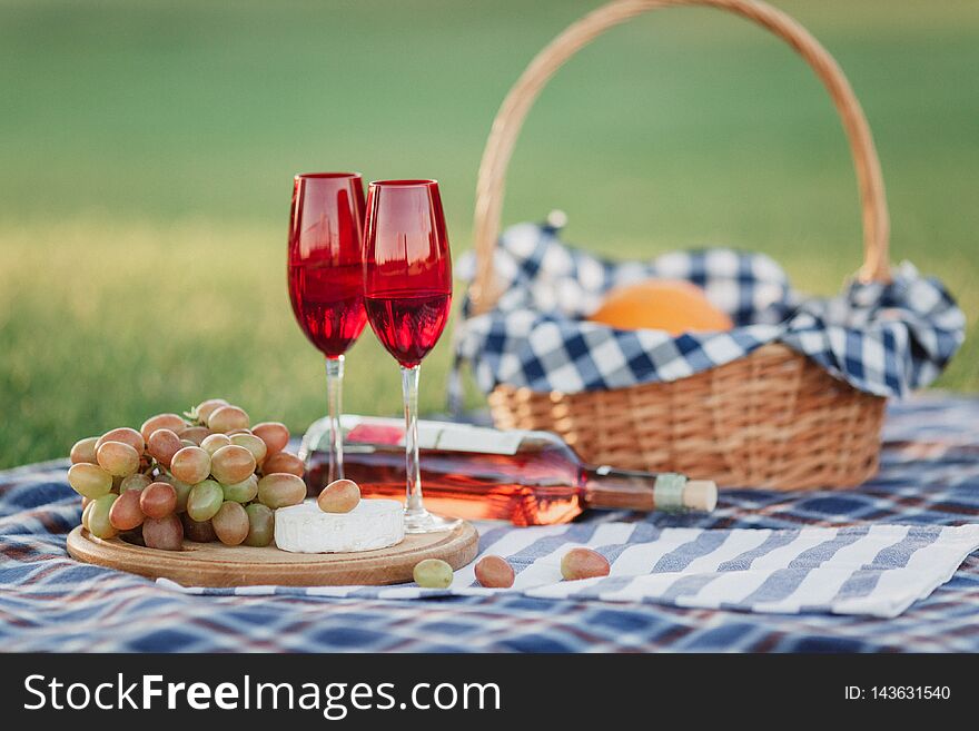 Picnic basket with drinks, food and fruit on green grass outside in summer park. Picnic theme. Summer pastime concept