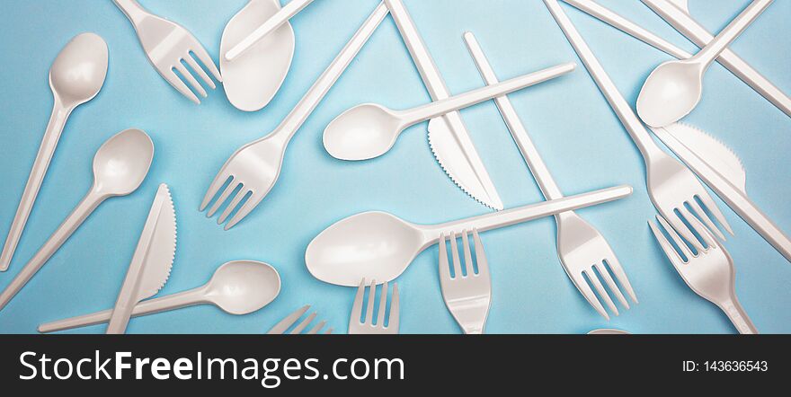 Single-use plastic products: plastic cutlery, cups on bright blue background