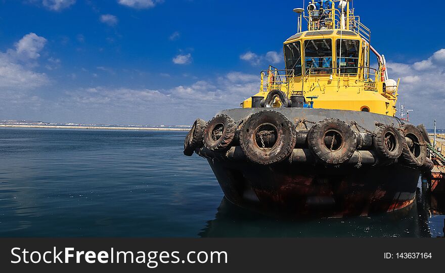 The tug is at the pier in the sea port. Panoramic view on  sea port