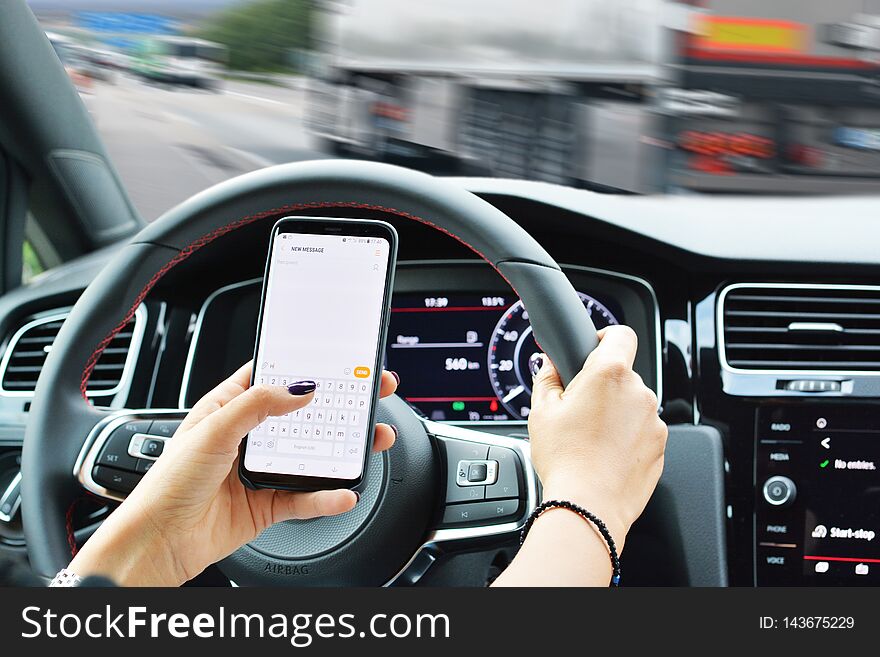 Risk of accident concept with woman texting on smartphone while driving. Risk of accident concept with woman texting on smartphone while driving