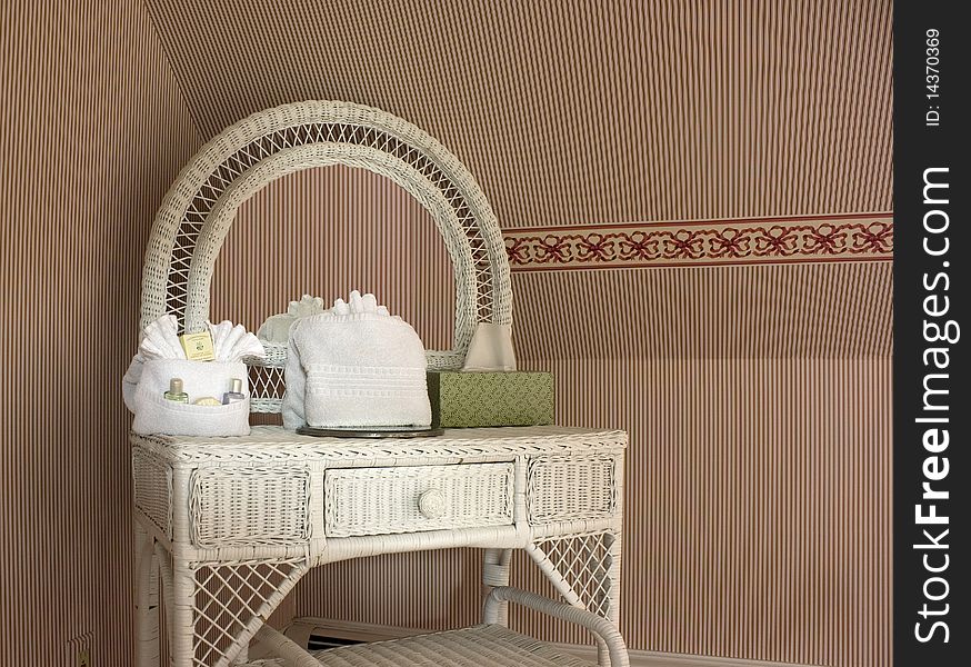 Wicker vanity table with striped wallpaper in an inn