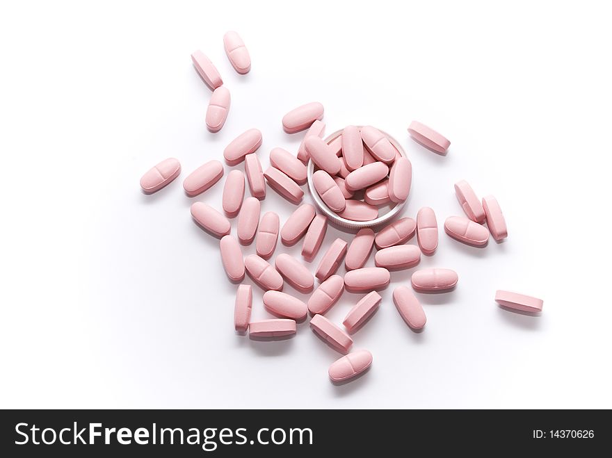 Pink pills lying on a white surface and the lid of the bubble of drugs. Pink pills lying on a white surface and the lid of the bubble of drugs