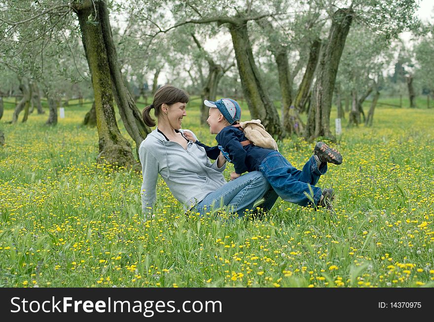 Mother and child playing in an olive grove in the meadow of dandelions. Mother and child playing in an olive grove in the meadow of dandelions.