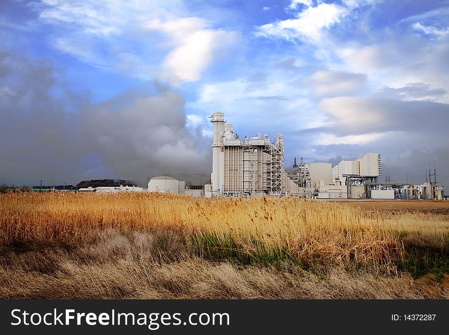 Power plant with wheat grass in the foreground and blue sky's with clouds