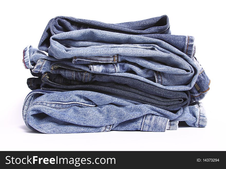Stack of folded blue jeans on white background