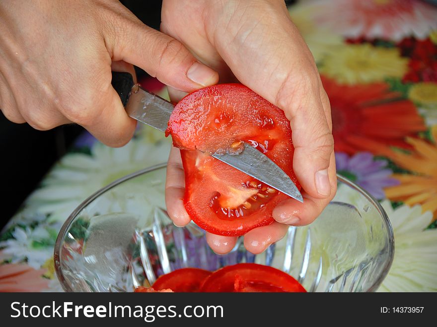 Woman hands closeup cutting a red ripe tomato for salad. Woman hands closeup cutting a red ripe tomato for salad