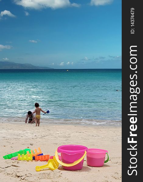 The children toys on beach . Motioned people (father and son) are plying on the beach. Tropical sea , sky, island on horizon as background. The area of sky is free for your text . The children toys on beach . Motioned people (father and son) are plying on the beach. Tropical sea , sky, island on horizon as background. The area of sky is free for your text .