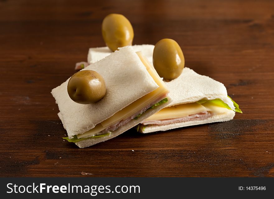 Photo of sandwich with lettuce, cheese and ham putted on a wood table