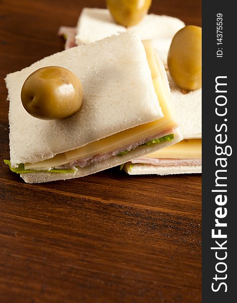 Photo of sandwich with lettuce, cheese and ham putted on a wood table