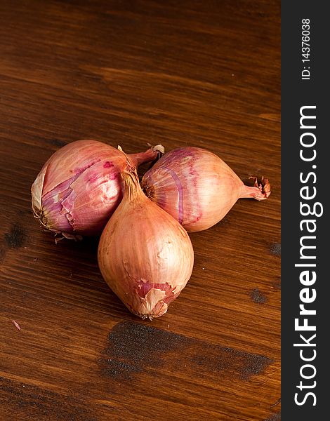 Photo of three onions putted on a wood table