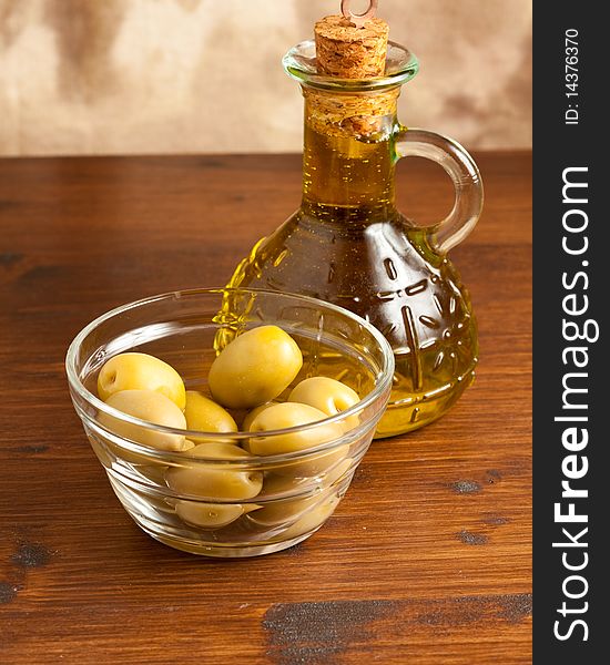 Photo of green olives in a bowl standing on a wood table