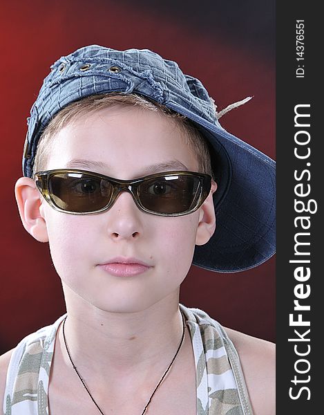 Portrait of is 10-11 years old boy in a jean cap and sun glasses. Portrait of is 10-11 years old boy in a jean cap and sun glasses