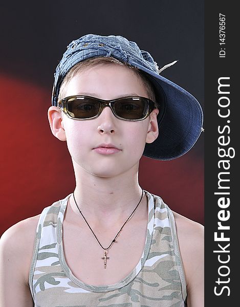 Portrait of is 10-11 years old boy in a jean cap and sun glasses. Portrait of is 10-11 years old boy in a jean cap and sun glasses