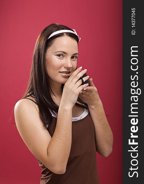 Beautiful young brunette drinking coffee in the studio with rear blym background