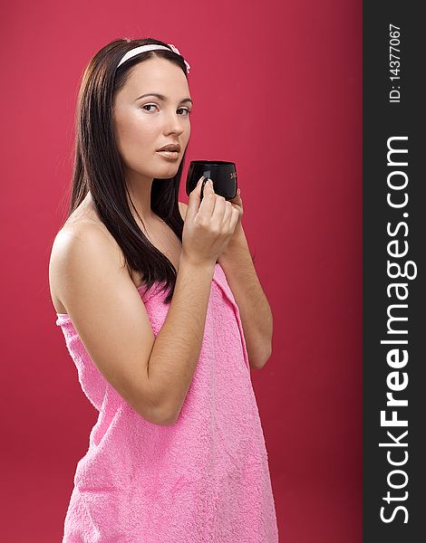 Beautiful young brunette drinking coffee in the studio with rear blym background