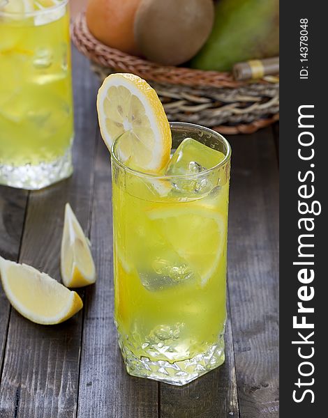 Cold lemon beverage in a wet glass with pieces of the fruit. Cold lemon beverage in a wet glass with pieces of the fruit