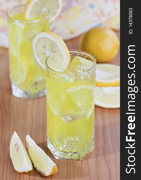 Cold beverage of lemon fruit with ice cubes on wooden table top