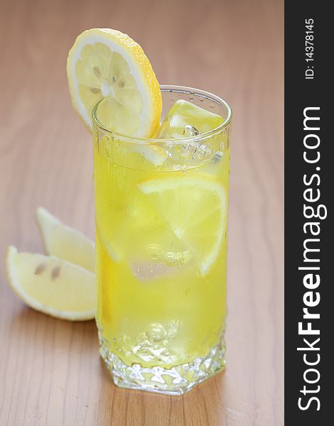 Glass of cold lemon beverage on wooden table top