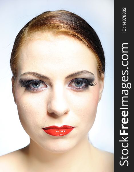 Young beauty female face with red shiny lips and black eye makeup. colse-up.