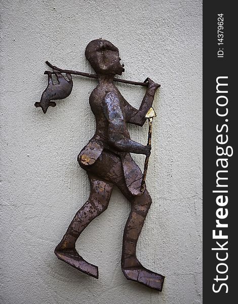 A rusted metal figurine of a native hunter walking with a catch