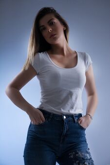 Low Key Girl Portrait With Blonde Hair In White T Shirt And Blue Jeans And Hands In Pockets Royalty Free Stock Images