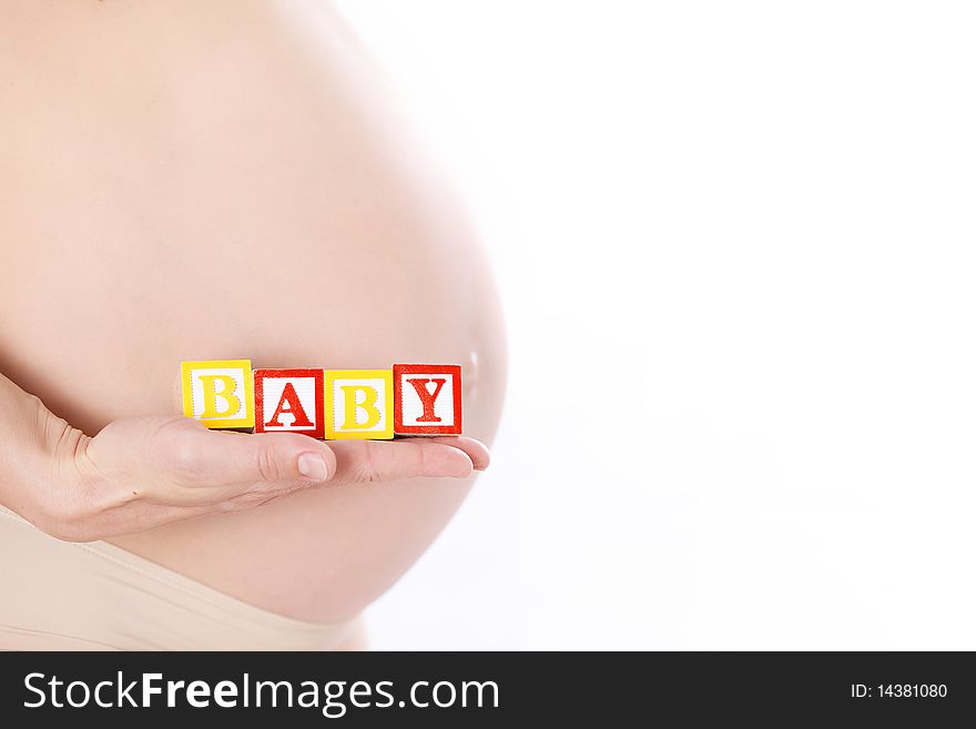 Pregnant belly with wooden playing blocks spelling the word Baby