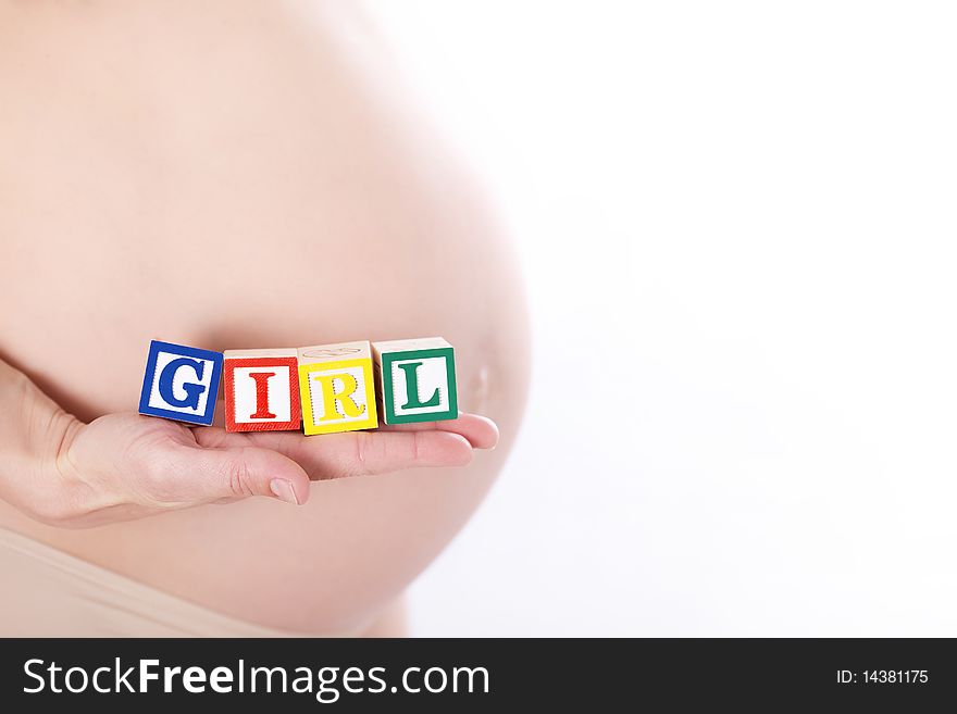 Pregnant belly with wooden playing blocks spelling the word Girl