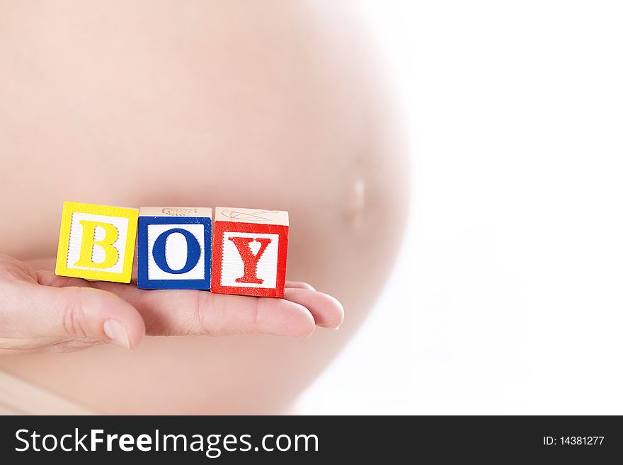 Pregnant belly with wooden playing blocks spelling the word Boy