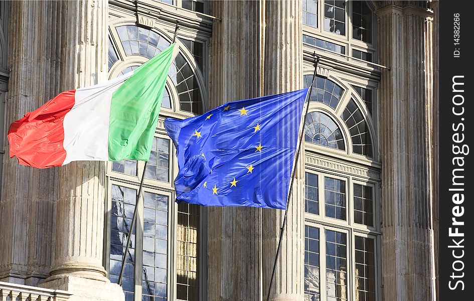 Italian and Eurpean flag in wind on monument facade