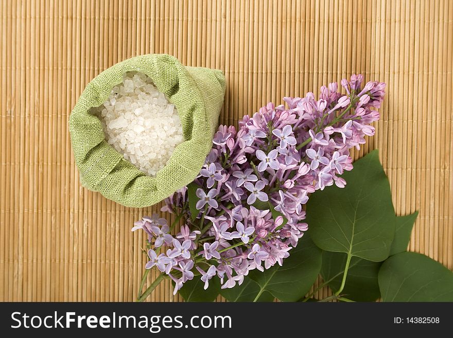 Branch of lilac and green bag with scattered sea salt. Branch of lilac and green bag with scattered sea salt