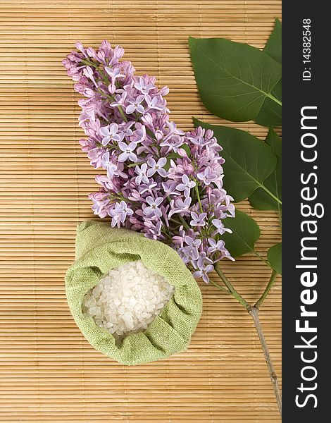 Branch of lilac and green bag with scattered sea salt. Branch of lilac and green bag with scattered sea salt