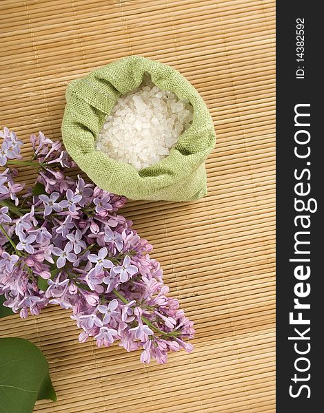 Branch of lilac and green bag with scattered sea salt. Branch of lilac and green bag with scattered sea salt