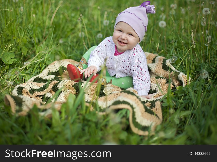 Baby On The Grass, In The Jumper And Booties