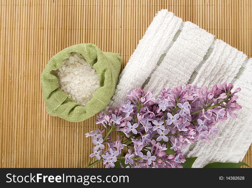 Towel, a branch of lilac and green bag with scattered sea salt. Towel, a branch of lilac and green bag with scattered sea salt