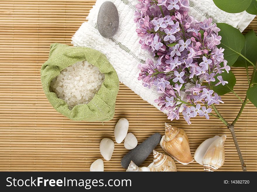 Towel, a branch of lilac and green bag with scattered sea salt. Towel, a branch of lilac and green bag with scattered sea salt