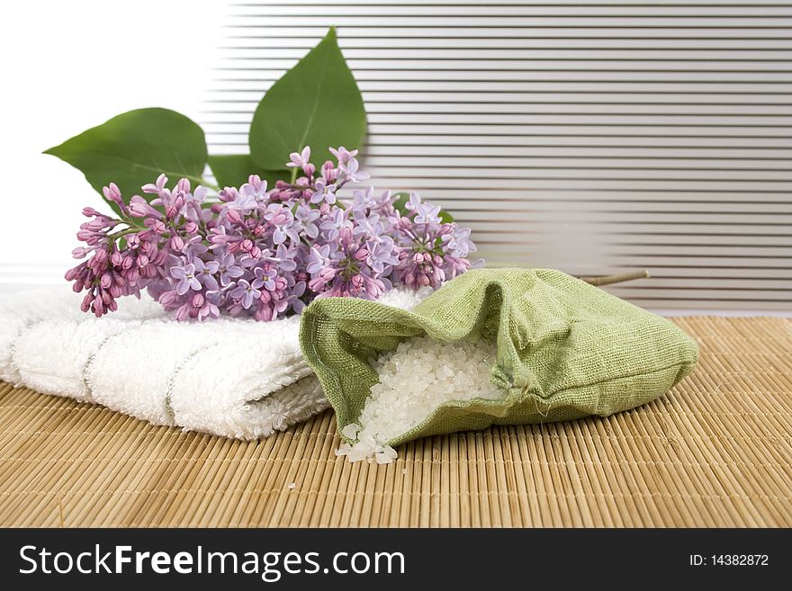 Towel, a branch of lilac and green bag with scattered sea salt. Towel, a branch of lilac and green bag with scattered sea salt