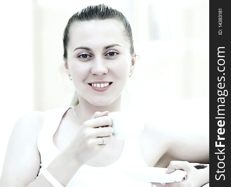 Happy young woman in white with cup of coffee or tea at home. Happy young woman in white with cup of coffee or tea at home