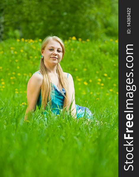 Pretty smiling blonde girl relaxing in grass outdoor